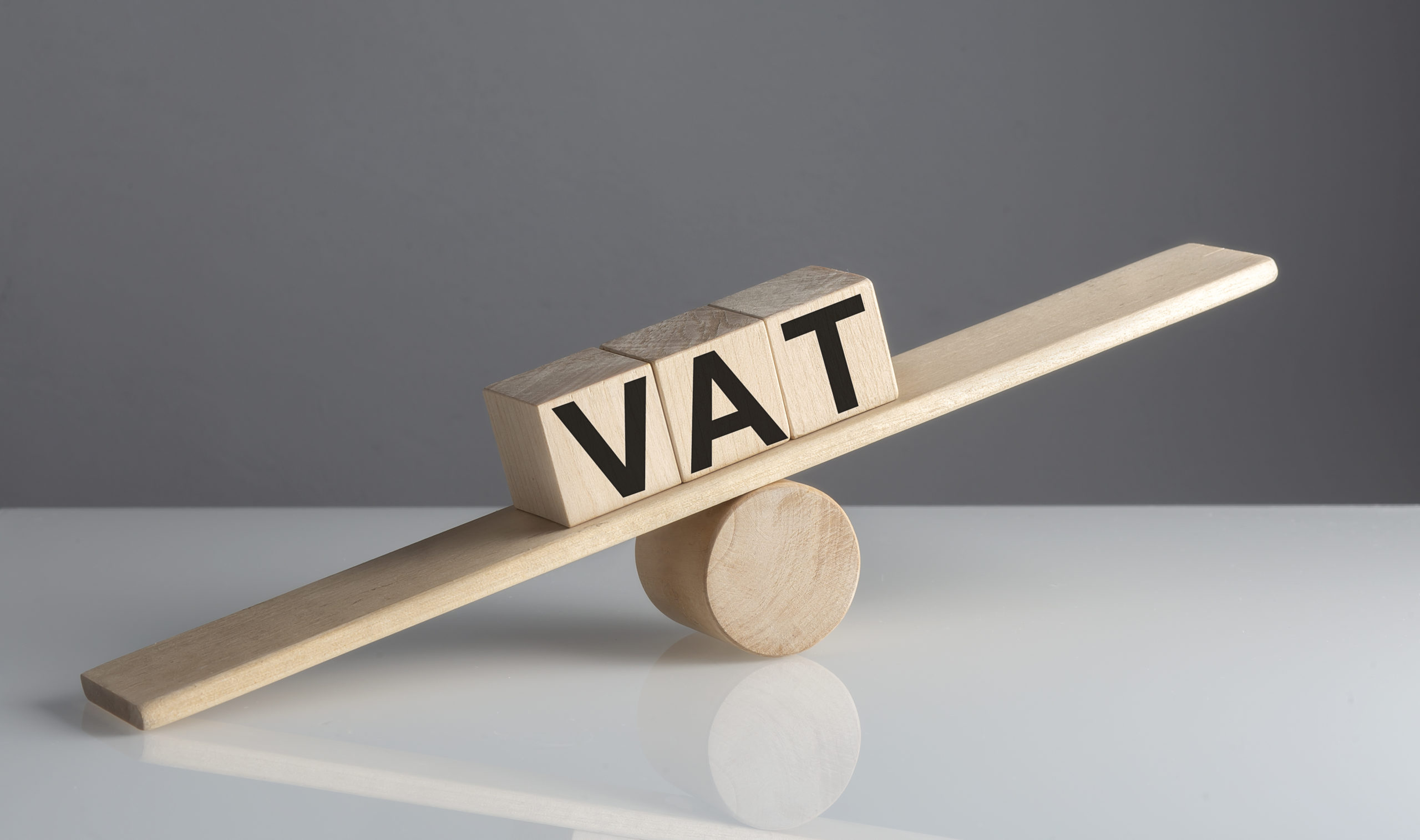 Vat on wooden cubes on a wooden balance , business concept